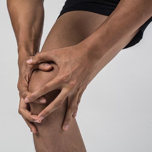 Young sport man with strong athletic legs holding knee with his hands in pain after suffering ligament injury  isolated on white.