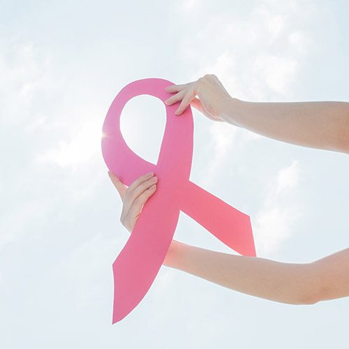Woman showing pink ribbon to support breast cancer.