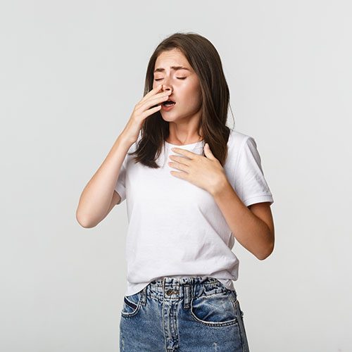 Young woman with allergy sneezing. Girl feeling sick having runny nose.